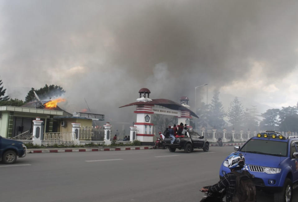 Residents drive past a burning government building in Wamena, Papua province, Indonesia, Monday, Sept. 23, 2019. Hundreds of protesters in Indonesia's restive Papua province set fire to homes and other buildings Monday in a protest sparked by rumours that a teacher had insulted students. (AP Photo/George Yewun)