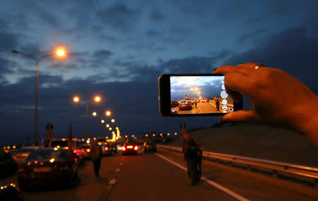 People gather before a trip along a bridge, which was constructed to connect the Russian mainland with the Crimean Peninsula across the Kerch Strait, Crimea May 16, 2018. REUTERS/Pavel Rebrov