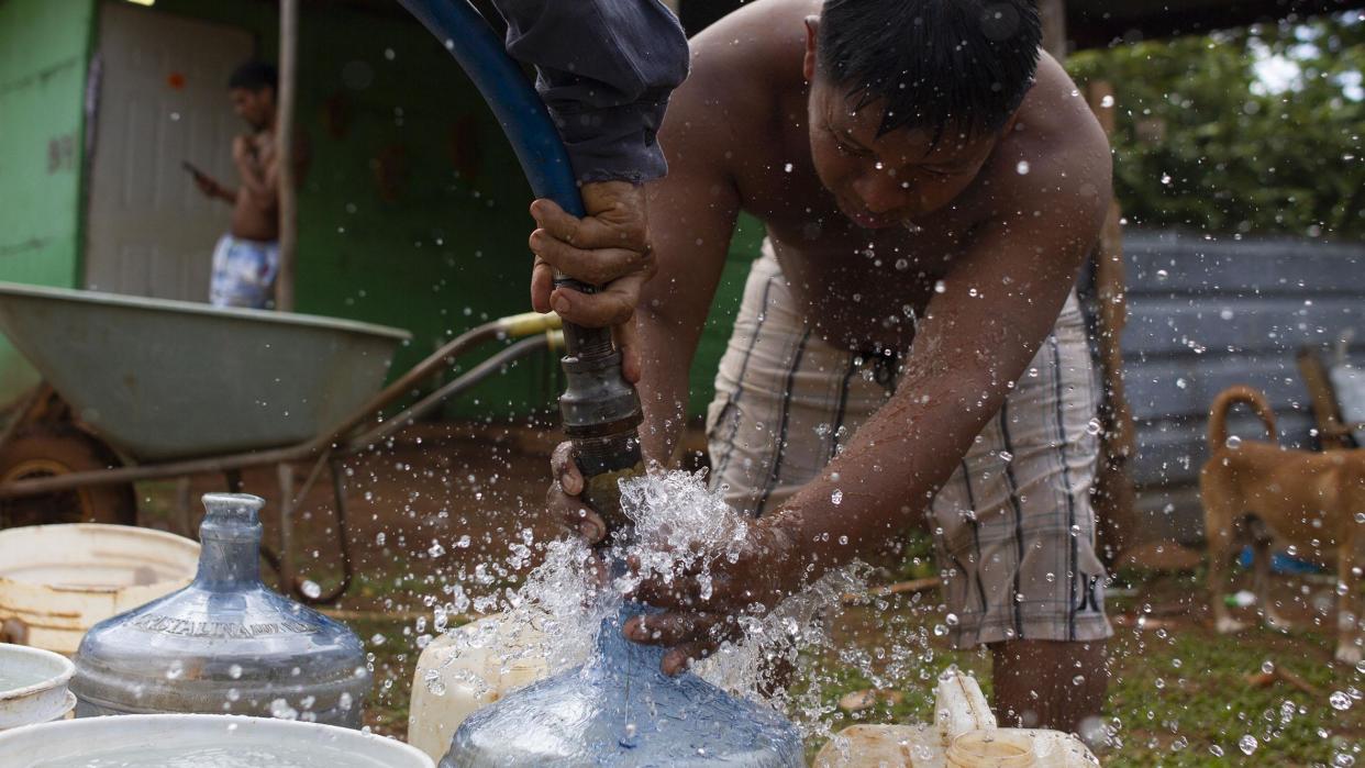 Joven llena garrafas de agua de manguera de camión cisterna