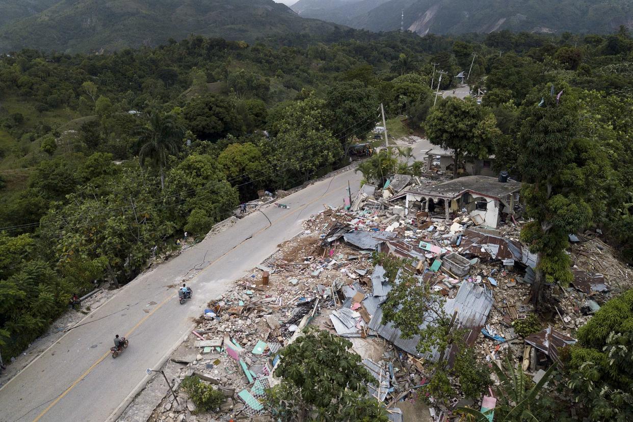 Homes lay in ruins along an earthquake-damaged road in Rampe, Haiti, Wednesday, Aug. 18, 2021, four days after a 7.2-magnitude earthquake hit the southwestern part of the country.