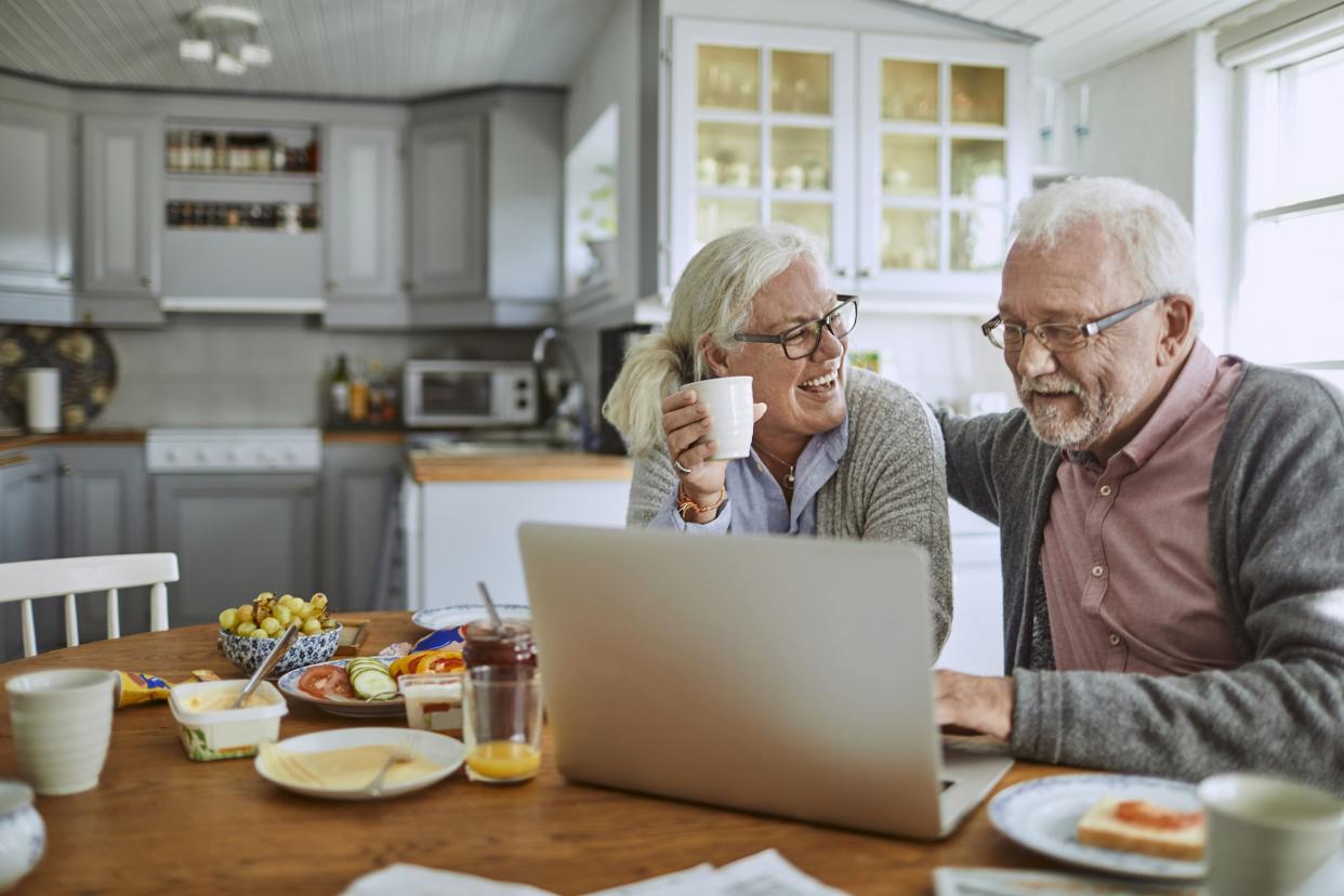 senior couple having breakfast and using a laptop