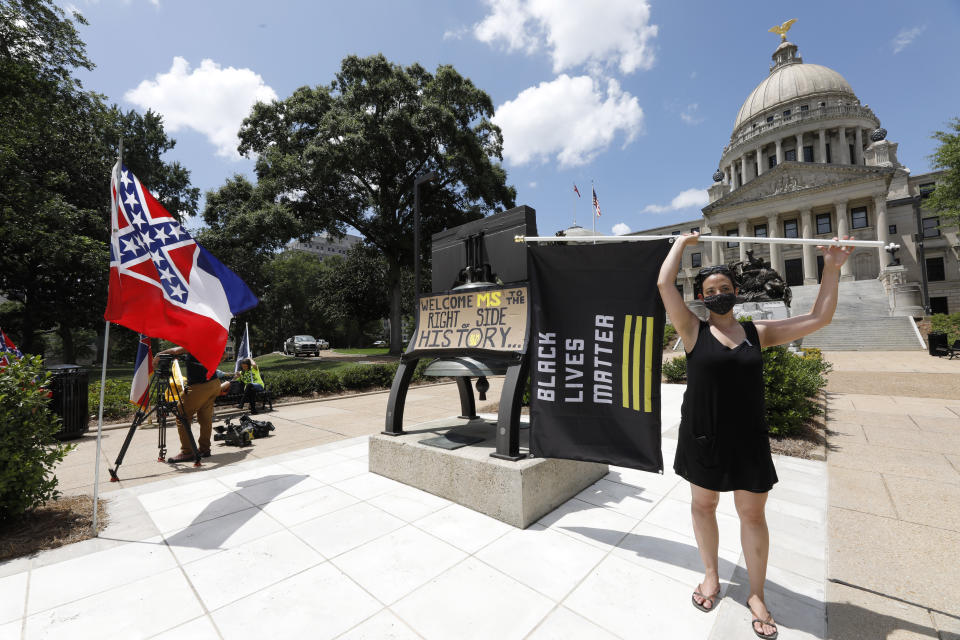 Paloma Wu holds a Black Lives Matter banner while calling for a new Mississippi state flag, while current flag supporters wave the flag as both sides make their sentiments known as lawmakers are expected to debate state flag change legislation Sunday, June 28, 2020, at the Capitol in Jackson, Miss. Mississippi Governor Tate Reeves has already said he would sign whatever flag bill the Legislature decides on. (AP Photo/Rogelio V. Solis)