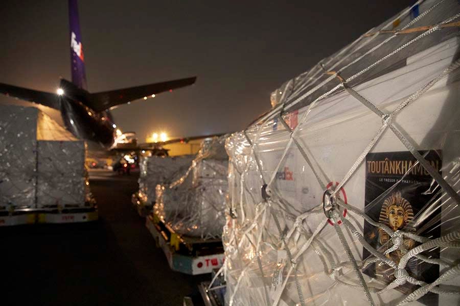 Ancient artifacts in a King Tut exhibit that FedEx Express and FedEx Custom Critical helped transport sit behind a FedEx plane awaiting their next stop.