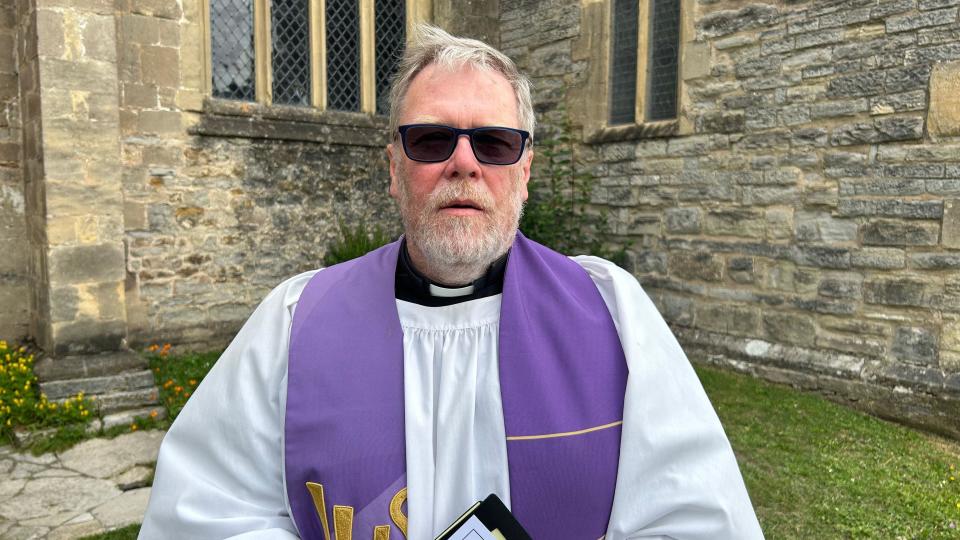 Vicar of St John The Baptist Church, David MacGeoch, dressed in his official robes, stood next to the stone church