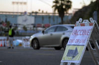 Drivers with a vaccine appointment enter a mega COVID-19 vaccination site set up in the parking lot of Dodger Stadium in Los Angeles Saturday, Jan. 30, 2021. One of the largest vaccination sites in the country was temporarily shut down Saturday because dozen of protesters blocked the entrance, stalling hundreds of motorists who had been waiting in line for hours, the Los Angeles Times reported. The Los Angeles Fire Department shut the entrance to the vaccination center at Dodger Stadium about 2 p.m. as a precaution, officials told the newspaper. The protesters had members of anti-vaccine and far-right groups, the Times reported. Some of them carried signs decrying the COVID-19 vaccine and shouting for people not to get the shots. (AP Photo/Damian Dovarganes)