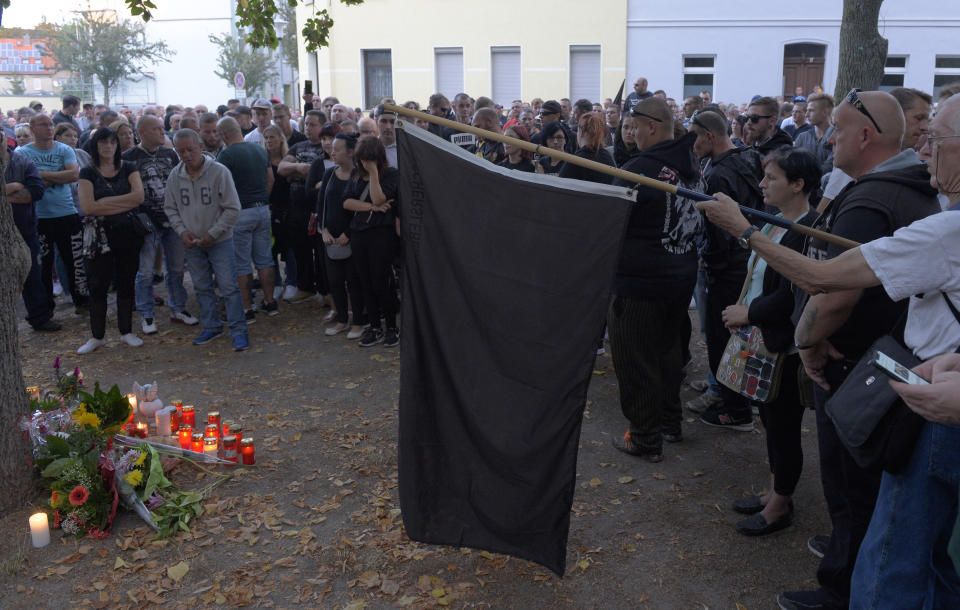 People gather at the site of a deadly brawl in Koethen, 90 miles southwest of the German capital Berlin, Sunday, Sept. 9, 2018, after police has arrested two Afghan men on suspicion of killing a 22-year-old German man. (AP Photo/Jens Meyer)