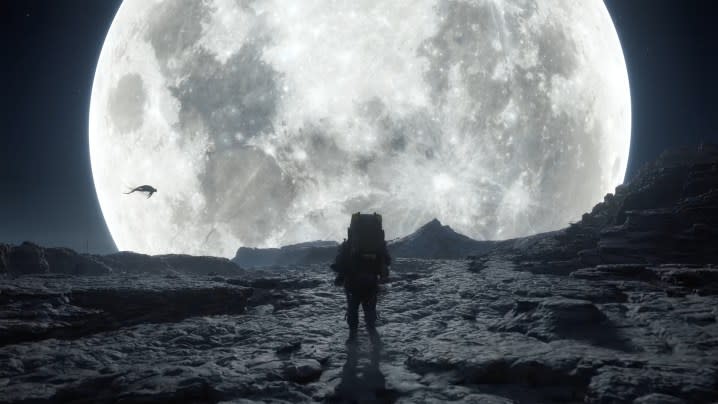 Sam Bridges walks on a ridge in front of the moon.