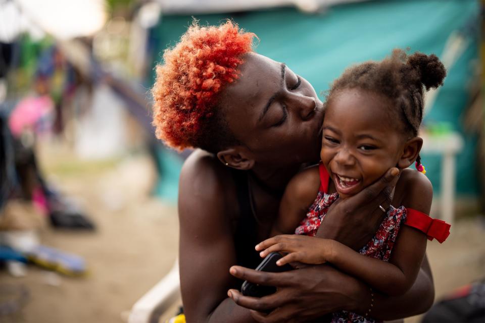 Ester Lundy playfully lavishes her daughter Amain with kisses in the migrant camp in Necoclí. | Spenser Heaps, Deseret News