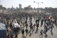 Protesting farmers run for cover as police use water cannon to disperse them, as they attempt to move towards Delhi, at the border between Delhi and Haryana state, Friday, Nov. 27, 2020. Thousands of agitating farmers in India faced tear gas and baton charge from police on Friday after they resumed their march to the capital against new farming laws that they fear will give more power to corporations and reduce their earnings. While trying to march towards New Delhi, the farmers, using their tractors, cleared concrete blockades, walls of shipping containers and horizontally parked trucks after police had set them up as barricades and dug trenches on highways to block roads leading to the capital. (AP Photo/Altaf Qadri)