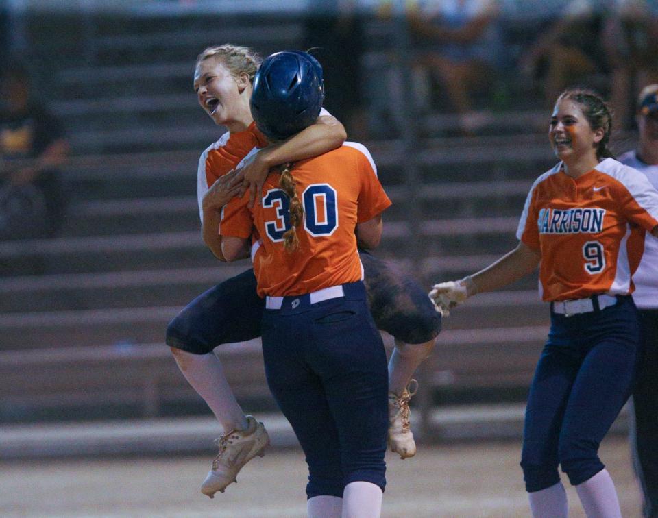 Harrison Raiders Whitney Duell (11) jumps on Jadyn Ramer (30) after Ramer won the 2022-23 IHSAA Class 4A softball state tournament match against the Logansport Berries with a last minute hit at the bottom of the seventh inning, Tuesday, May 23, 2023, at Harrison High School in West Lafayette, Ind. Harrison won 3-2.