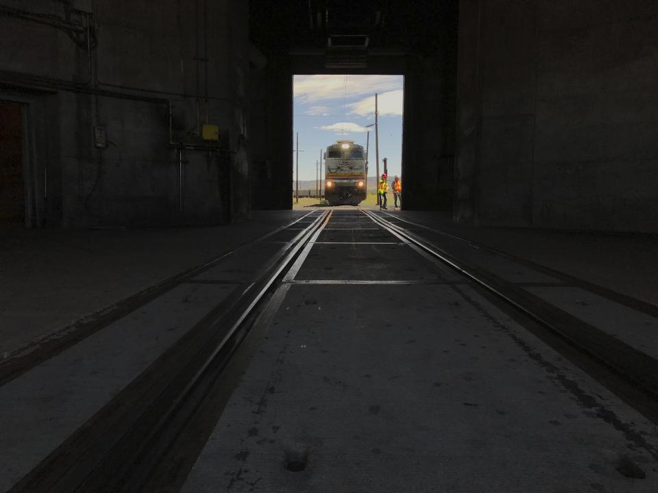 This Aug. 20, 2019, image shows an electric train puling into a coal silo that is fed by a mine near Kayenta, Ariz. The train picked up its final load for the Navajo Generating Station in late August 2019 as the coal-fired power plant prepared to close before the year ends. (AP Photo/Susan Montoya Bryan)