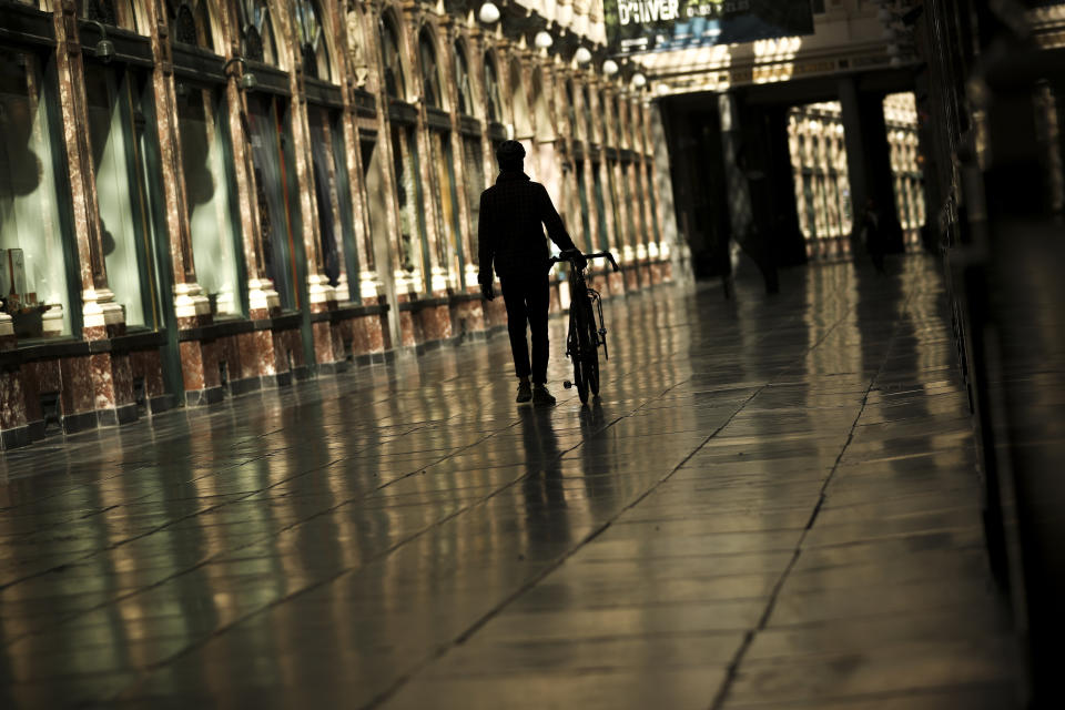A man walks along along a virtually empty Royal Gallery of Saint Hubert commercial street during a partial lockdown ordered by Belgium government in Brussels, Tuesday, March 24, 2020. For some people the COVID-19 coronavirus causes mild or moderate symptoms, but for some it causes severe illness. (AP Photo/Francisco Seco)