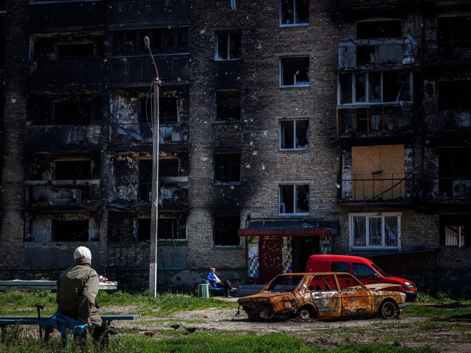 Local residents sit next next to a damaged apartment building in the town of Irpin, near Kyiv, on May 31, 2022, amid the Russian invasion of Ukraine.