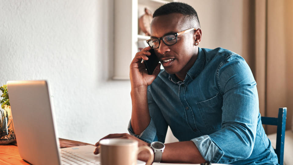 Cropped shot of a handsome young businessman sitting alone in his home office and talking on his cellphone.