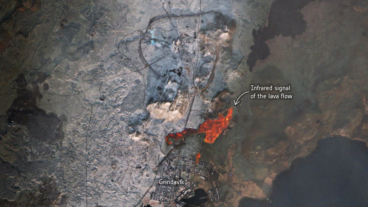  A satellite image of buildings with a glowing pool of lava beside. 