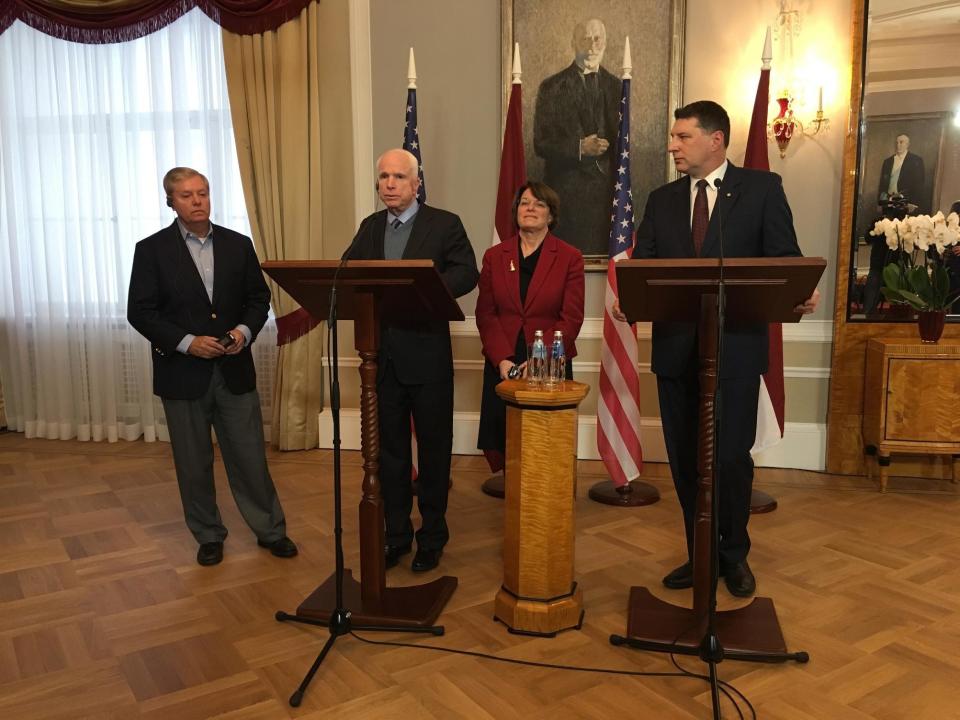 Latvian President Raimonds Vejonis, right, looks at US Sen. John McCain centre left, during a press conference, Wednesday, Dec. 28, 2016 in Riga, Latvia, while Lindsey Graham, R-SC., and Amy Klobuchar, D-Minn., stand in the background. Russia can expect hard-hitting sanctions from United States lawmakers if an investigation proves that Moscow interfered in the presidential election, a U.S. senator said Wednesday during a visit to Latvia. (AP Photo/Vitnija Saldava)