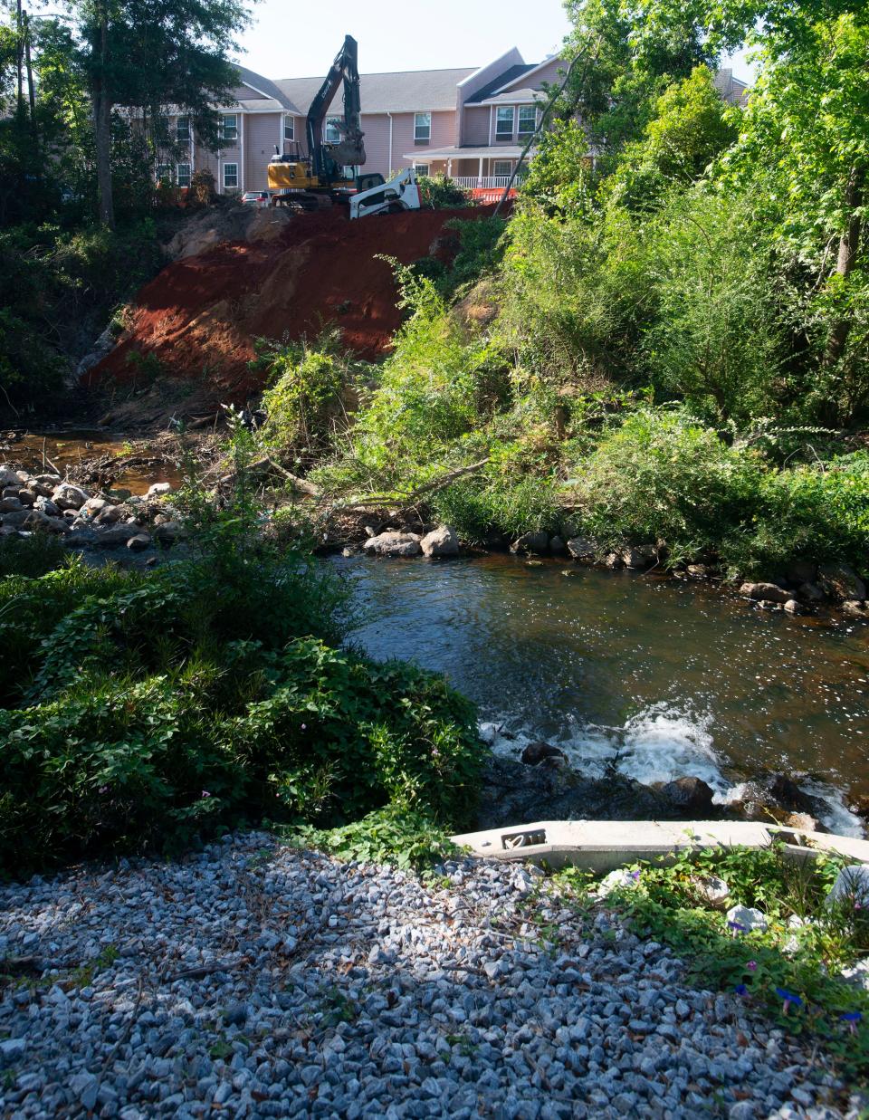 A contractor pushes red clay over an embankment April 28, allowing the sediment to enter the Carpenter Creek watershed in an effort to stabilize a nearby parking lot.