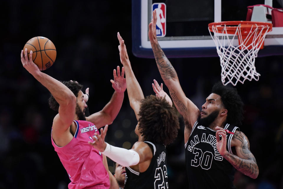 Washington Wizards forward Anthony Gill, left, goes up against San Antonio Spurs forwards Dominick Barlow (26) and Julian Champagnie (30) during the second half of an NBA basketball game Friday, March 24, 2023, in Washington. (AP Photo/Carolyn Kaster)