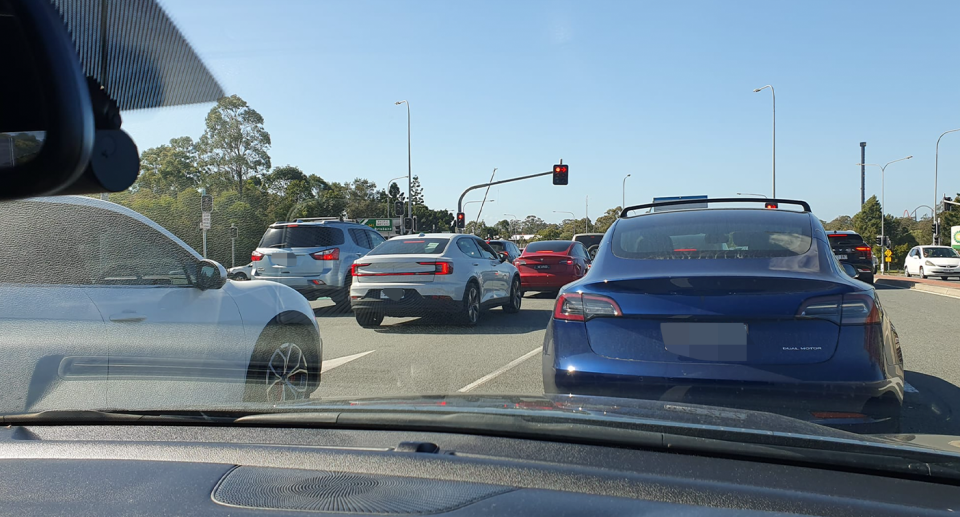 A set of traffic lights where almost every vehicle is an EV. 