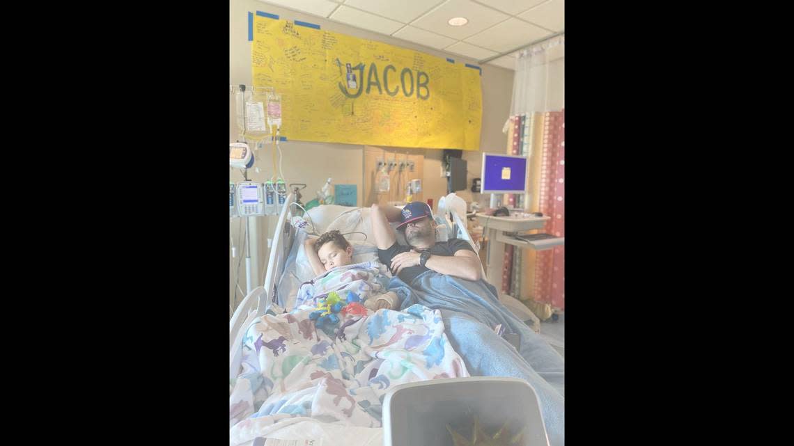 Anthony Estrada rests with his 7-year-old son Jacob. His son was severely injured in a car crash.