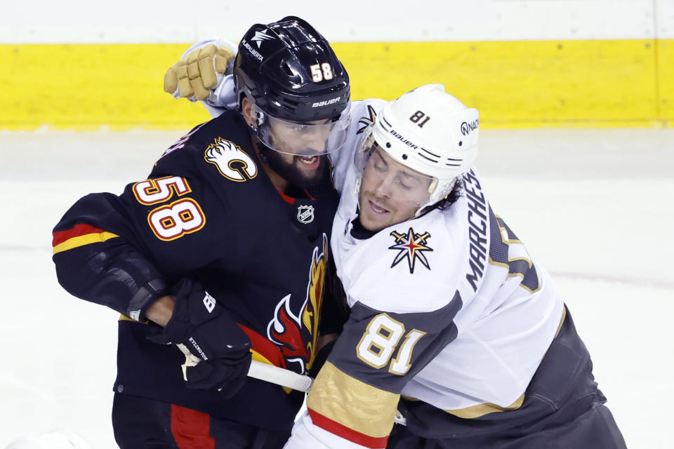 Vegas Golden Knights' Jonathan Marchessault, right, grabs Calgary Flames' Oliver Kylington during the second period of an NHL hockey game Thursday, March 14, 2024, in Calgary, Alberta. (Larry MacDougal/The Canadian Press via AP)