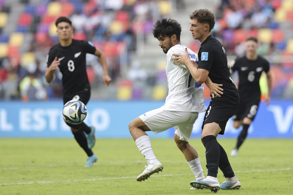 Uzbekistan's Shakhzod Akramov, center, battles for the ball with New Zealand's Adam Supyk during a FIFA U-20 World Cup group A soccer match at the Madre De Ciudades stadium in Santiago Del Estero, Argentina, Tuesday, May 23, 2023. (AP Photo/Nicolas Aguilera)