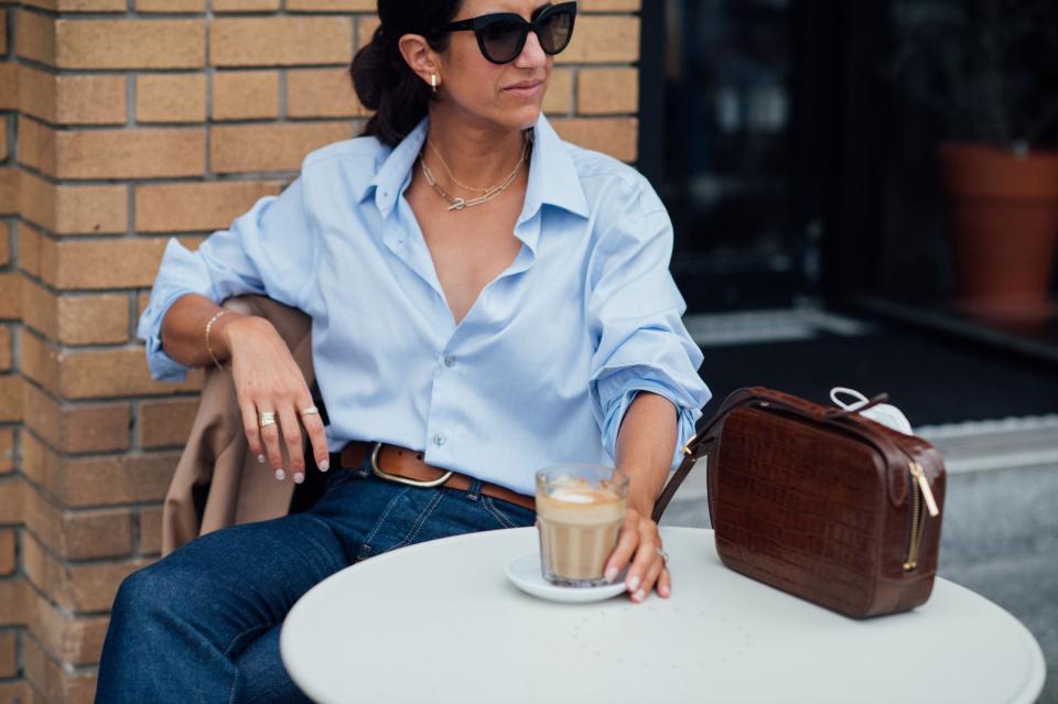 Alyssa Beltempo sits and drinks coffee in a blue shirt and jeans
