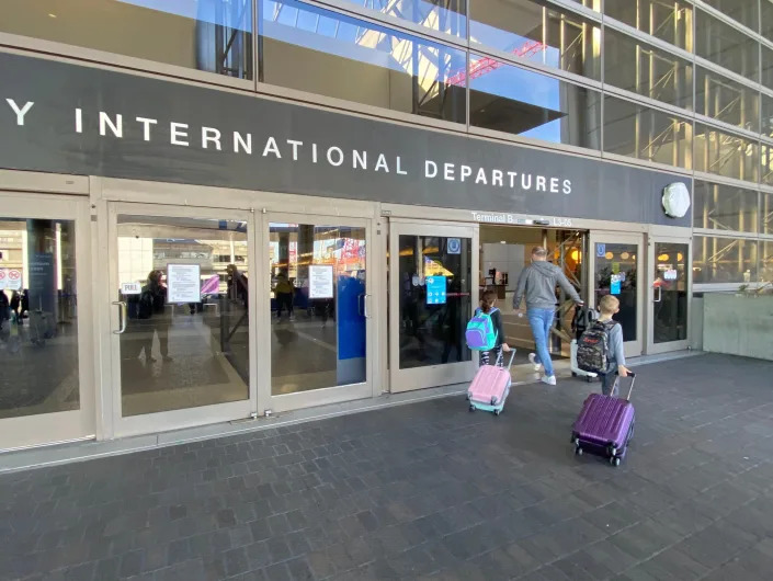 A family entering an international departures terminal at an airport.