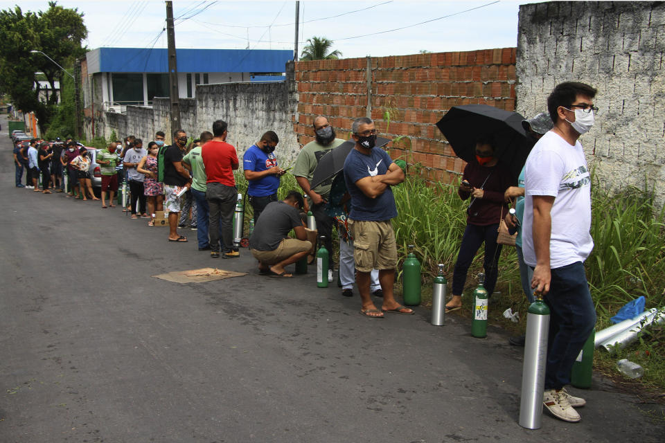 Family members of patients hospitalized with COVID-19 line up with empty oxygen tanks in an attempt to refill them, outside the Nitron da Amazonia company, in Manaus, Amazonas state, Brazil, Friday, Jan. 15, 2021. (AP Photo/Edmar Barros)