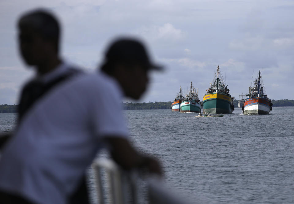 FILE - In this April 4, 2015, file photo fishing boats carrying recently rescued fishermen sail toward the town of Tual, Indonesia. The rescued fishermen were among hundreds of migrant workers revealed in an Associated Press investigation to have been lured or tricked into leaving their countries and were brought to Indonesia to be forced to catch seafood. A tuna fishing boat based in the Pacific island nation of Fiji that has been accused of essentially enslaving its crew was blocked Wednesday, Aug. 4, 2021, from importing seafood in the United States, part of an increasing effort to keep goods produced with forced labor from entering the country. (AP Photo/Dita Alangkara, File)