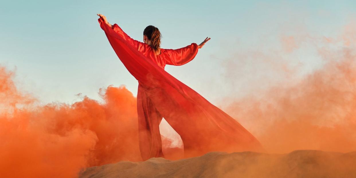 woman in red dress dancing in the desert at blue sky