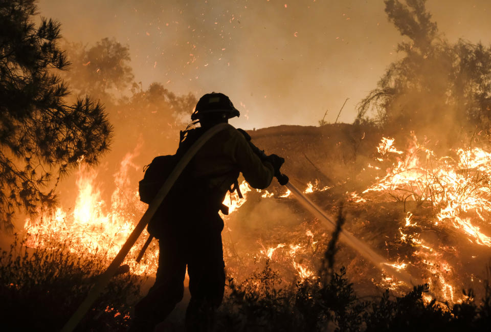 A firefighter battles the Holy Fire burning in the Cleveland National Forest along a hillside at Temescal Valley in Corona, Calif., Thursday, Aug. 9, 2018. Firefighters fought a desperate battle to stop the Holy Fire from reaching homes as the blaze surged through the Cleveland National Forest above the city of Lake Elsinore and its surrounding communities. (AP Photo/Ringo H.W. Chiu)
