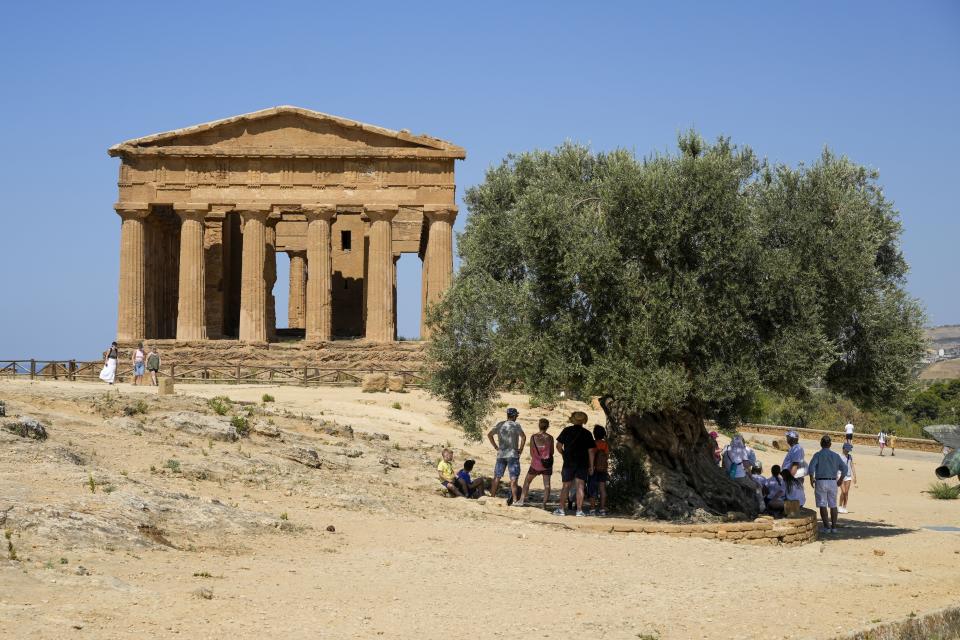 Visitors admire the ancient Greek Concordia temple, known as the Temple of Juno, in the Valley of the Temples archeological park, in Agrigento, southern Sicily, Italy, Thursday, July 18, 2024. (AP Photo/Andrew Medichini)