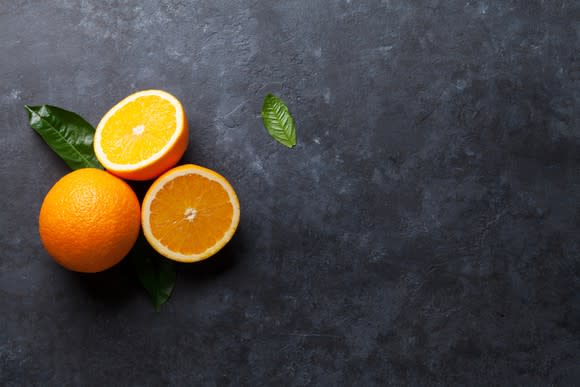 Oranges sitting on a black countertop.
