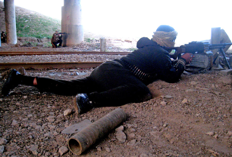 Gunmen take cover during clashes with Iraqi security forces outside Fallujah, 40 miles (65 kilometers) west of Baghdad, Iraq, Sunday, Jan. 19, 2014. Violence across Iraq, including a series of car bombings and fighting between militants and government troops over control of the country's contested Anbar province, killed dozens Saturday, officials said. (AP Photo)