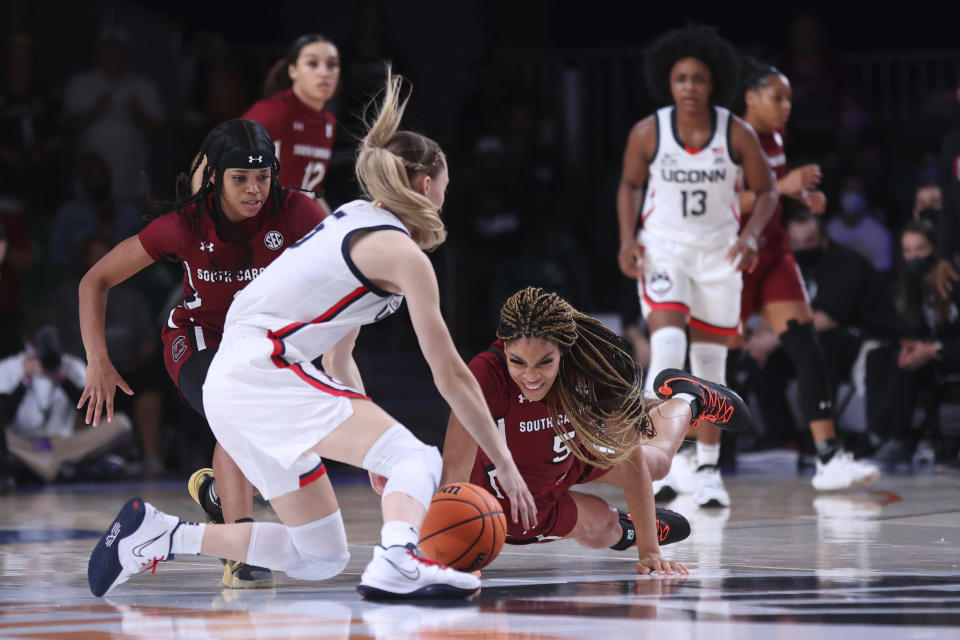 In this photo provided by Bahamas Visual Services, South Carolina forward Victaria Saxton (5), right, guard Destanni Henderson (3), left, and UConn guard Paige Bueckers (5), foreground, fight for ball possession during an NCAA college basketball game at Paradise Island, Bahamas, Monday, Nov. 22, 2021. (Tim Aylen/Bahamas Visual Services via AP)