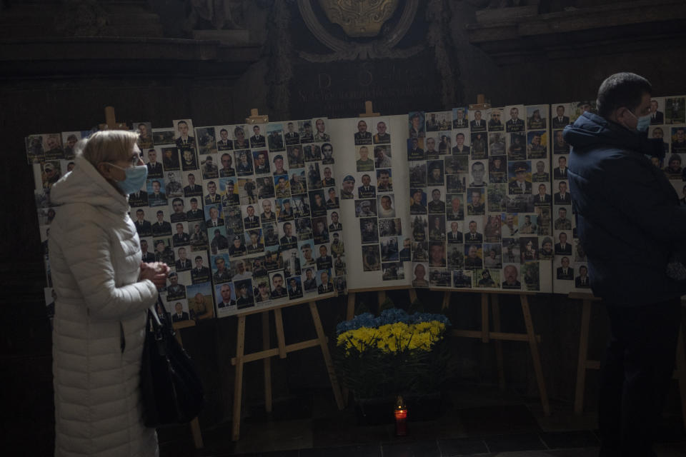 Christian worshipers stand next to fallen soldiers' memorial during Sunday mass at the Saints Peter and Paul Garrison Church in Lviv, western Ukraine, Sunday, March 6, 2022. The memorial is dedicated to Ukrainian soldiers who died after 2014. (AP Photo/Bernat Armangue)