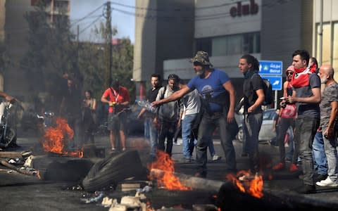 Anti-Government protesters set fire to tires blocking a road in the town of Jal el-Dib - Credit: AP Photo/Bilal Hussein