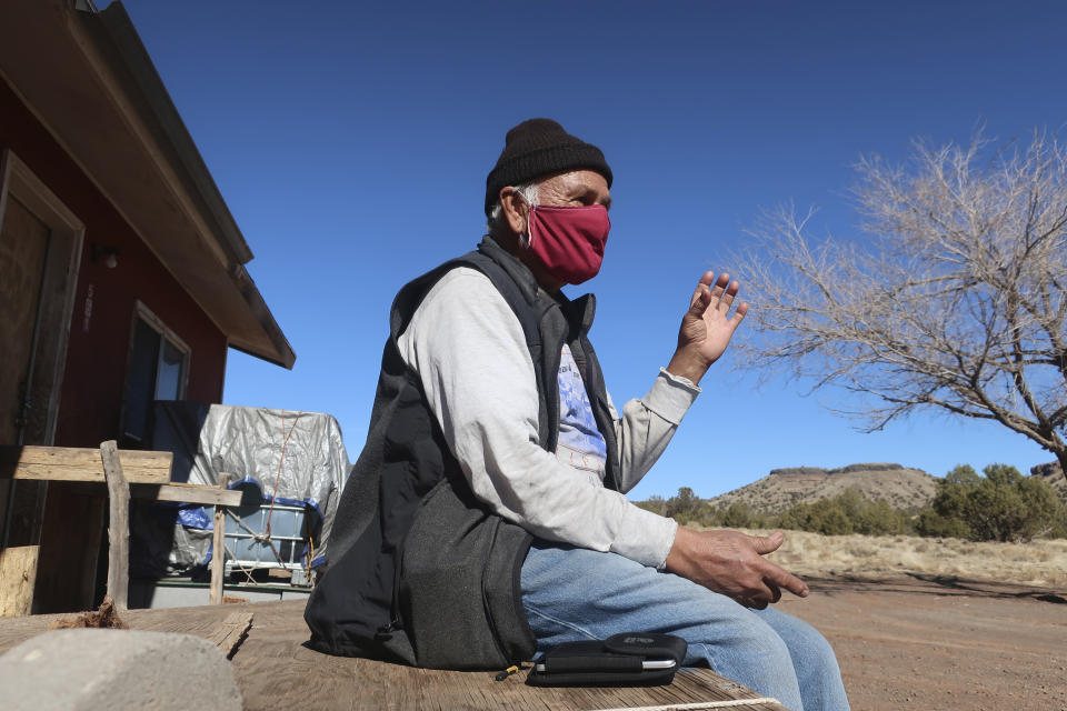 Raymond Clark sits outside his home in Teesto, Ariz., on the Navajo Nation on Thursday, Feb. 11, 2021. Teesto workers, health representatives, volunteers and neighbors keep close tabs on another to ensure the most vulnerable citizens get the help they need. (AP Photo/Felicia Fonseca)