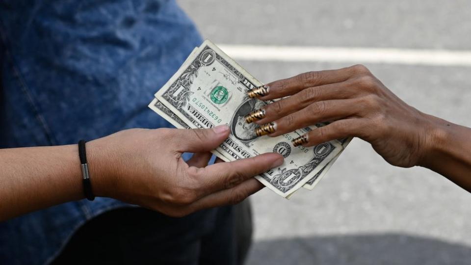 La mano de una mujer pagando en dólares