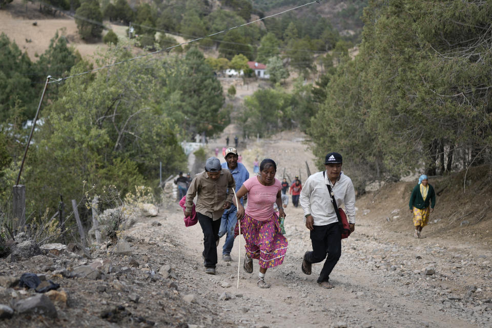 Rarámuri runner Teresa Sánchez is accompanied by residents as she competes in the Arihueta race in Cuiteco, Mexico, Saturday, May 11, 2024. “I always run in sandals,” Sánchez said. “I wear them every day and they last up to 2 or 3 years. (AP Photo/Eduardo Verdugo)