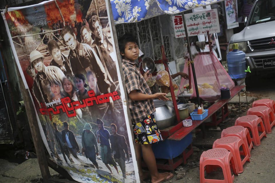 In this Tuesday, Aug. 13, 2013 photo, a Burmese boy mends a roadside food stall amidst the tightly packed enclave of video production houses, movie-poster design studios and worse-for-wear apartment buildings that serves as the tattered ground zero of the Burmese movie industry, in downtown Yangon, Myanmar. In the heart of Yangon's Little Hollywood, actors have been struggling for work as Myanmar opens up to a world brimming with pop-culture choices, and those who specialize in villainy have been hit particularly hard. They sit on tiny plastic chairs, glowering and stalking an ever-more-elusive quarry: a day's work. (AP Photo/Wong Maye-E)