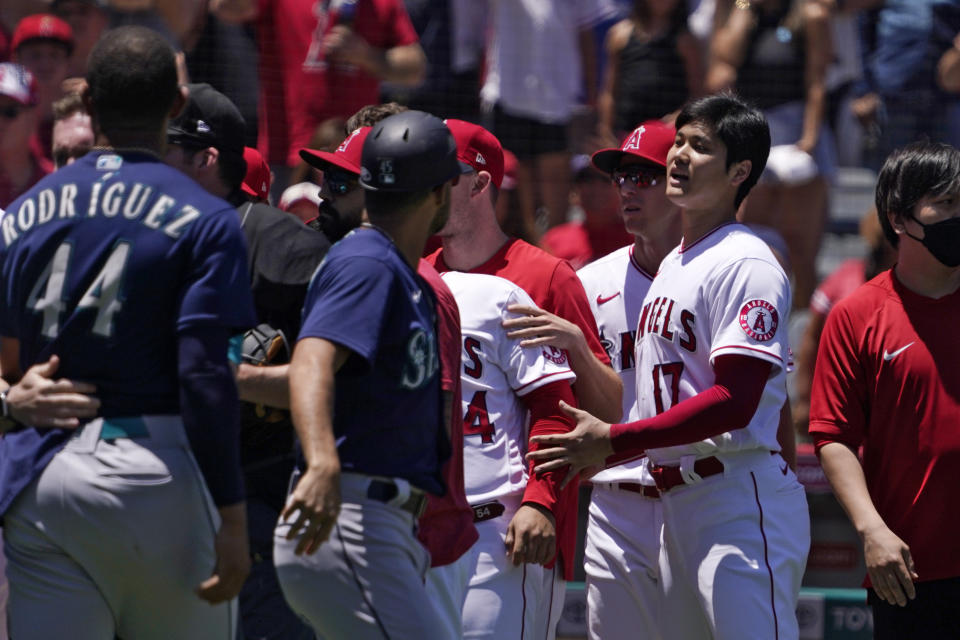 Seattle Mariners' Julio Rodriguez (44) is held back as Los Angeles Angels' Shohei Ohtani (17) watches while several members of the Mariners and the Angels scuffle after Mariners' Jesse Winker was hit by a pitch during the second inning of a baseball game Sunday, June 26, 2022, in Anaheim, Calif. (AP Photo/Mark J. Terrill)