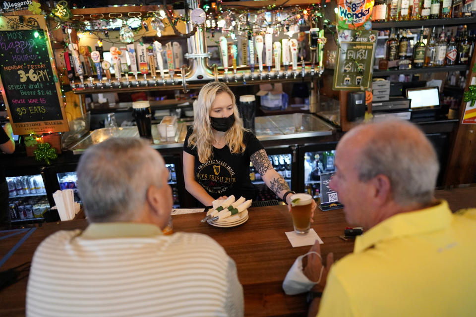 Bartender Angie Gibson, center, waits on customers at Mo's Irish Pub Wednesday, March 10, 2021, in Houston. Texas Gov. Greg Abbott allowed the state mandates for COVID-19 safety measures to expire Wednesday. (AP Photo/David J. Phillip)