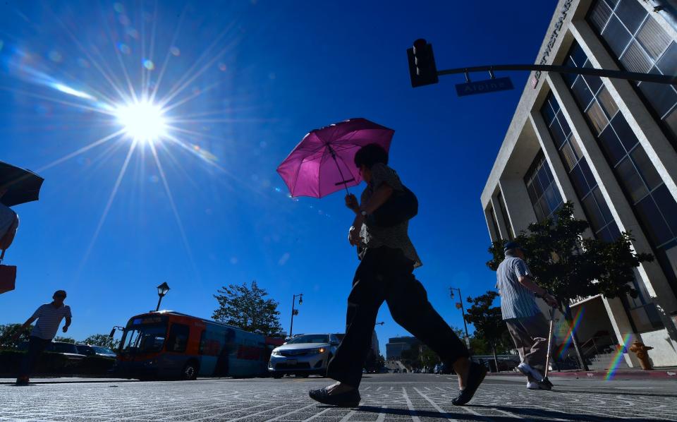 A pedestrian uses an umbrella as a heat shield in Los Angeles on Tuesday,&nbsp;when temperatures climbed past 100 downtown. (Photo: FREDERIC J. BROWN via Getty Images)