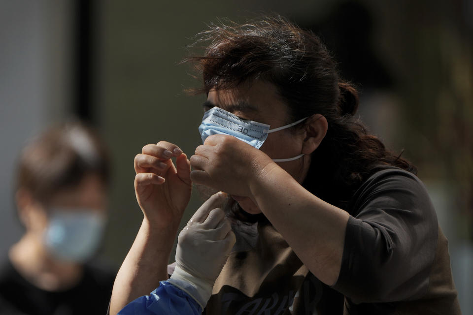 A woman pulls up her mask to get her routine COVID-19 throat swab at a coronavirus testing site in Beijing, Monday, Sept. 5, 2022. (AP Photo/Andy Wong)