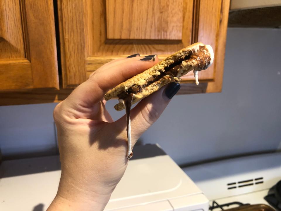 hand holding microwave smore in front of a cabinet