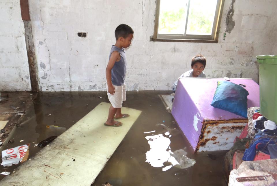 <p>Two children look at the flooding in a house on the Marshall Islands in 2014. The low-lying Pacific nation is among one of the most vulnerable to sea-level rise from climate change </p> (AFP via Getty Images)