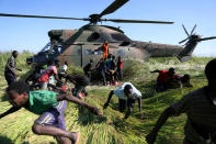 Varias personas corren tras recoger ayuda alimentaria de un helicóptero de las Fuerzas de Defensa de Sudáfrica en la aldea de Nhamatanda (Mozambique) días después del paso del ciclón Idai. Fotografía del 26 de marzo. (Foto: Siphiwe Sibeko / Reuters).