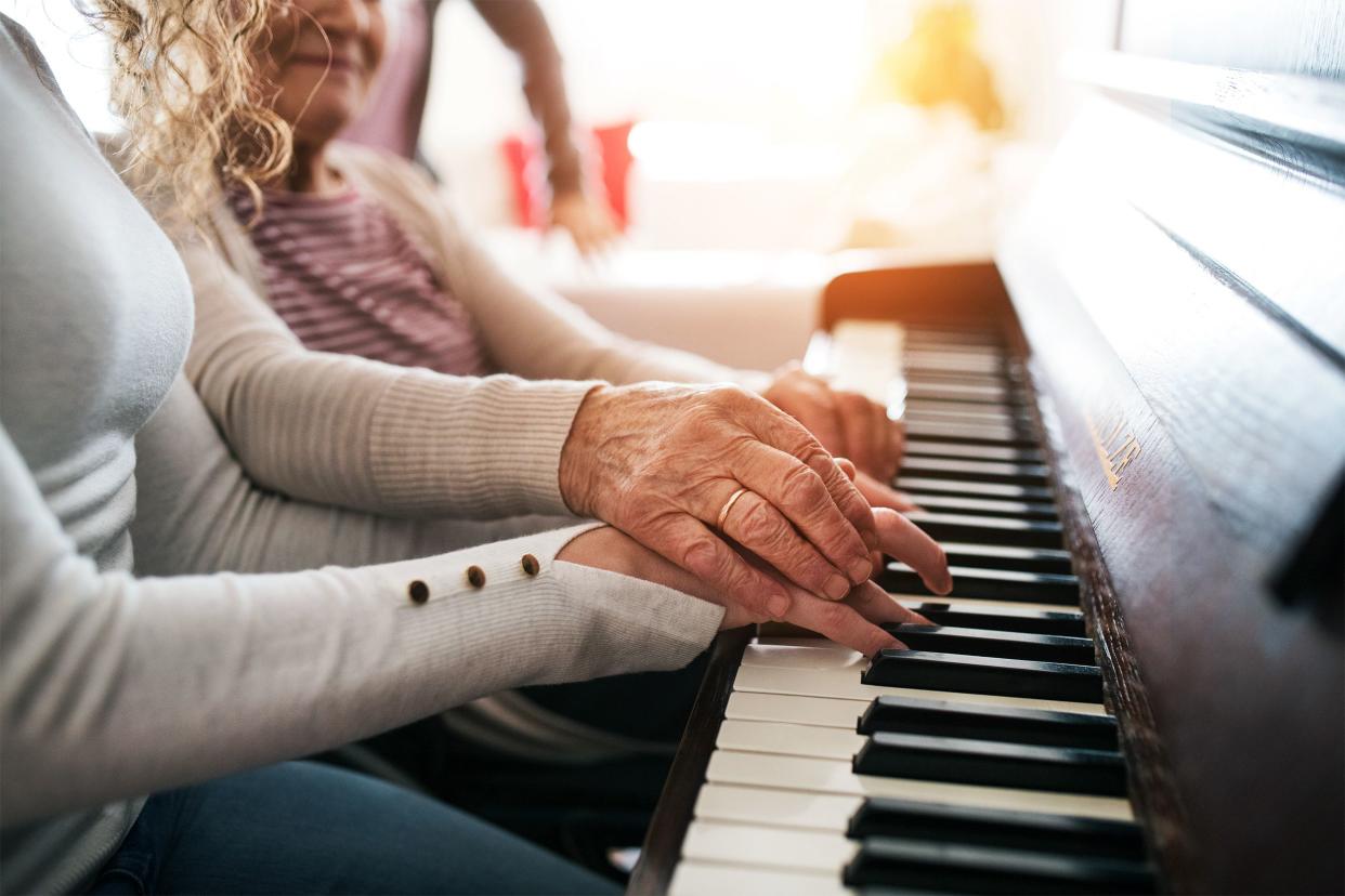Woman helping senior woman play the piano